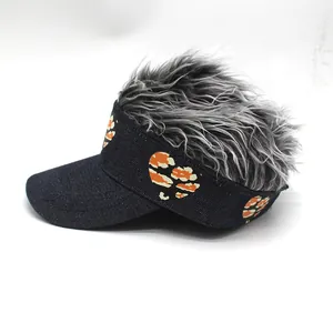 Detalle de la peluca gris y bordado de corazón de camuflaje naranja en visera azul