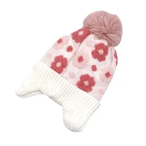 Détail du bonnet en tricot rose pour filles avec motifs floraux et pompon doux