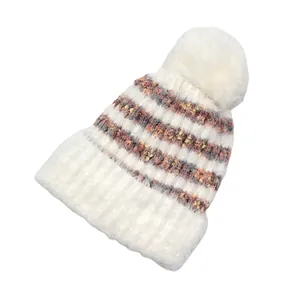 Détail du bonnet d'hiver en maille douce avec rayures colorées et pompon en fausse fourrure