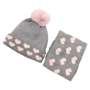 Detailed view of gray and pink heart pattern knitted hat and scarf set with pom-pom