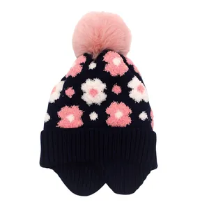 Détail du bonnet d'hiver pour fille avec motifs floraux et pompon en fausse fourrure