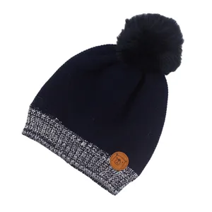 Detaillierte Ansicht einer dunkelblauen Strickmütze mit Bommel und Bären-Lederpatch