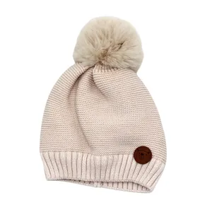 Detailansicht der Baby-Strickmütze mit Kunstfell-Pompon und niedlichem Bären-Patch