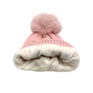 Détail du bonnet tricoté rose pour enfants avec doublure polaire blanche et pompon doux