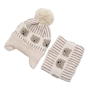 Detailed view of baby knit hat and scarf set featuring cute bear patch and soft pompom