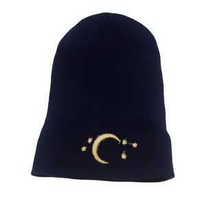 Close-up of yellow moon and stars embroidery on dark blue knitted beanie hat