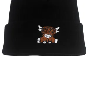 Close-up of a black knit beanie featuring a detailed colorful Highland Cow embroidery