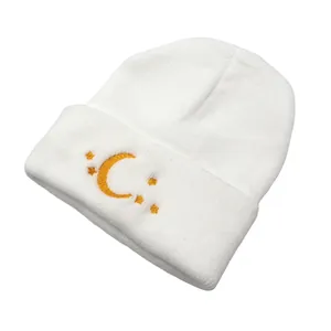 Close-up of golden moon and stars embroidery on a white knitted beanie hat