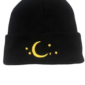 Detailed close-up of yellow moon and star embroidery on black knit beanie hat