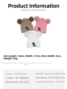 Detail of baby knitted hat with cartoon crocodile embroidery and twin pom-poms