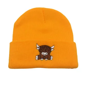 Detailed embroidery of a highland cow on an orange knitted winter beanie hat