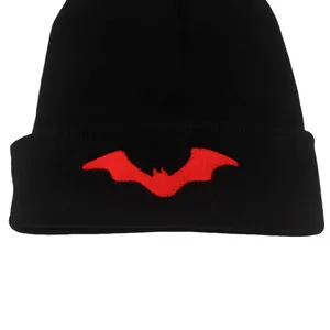 Dettaglio del ricamo a pipistrello rosso su un berretto in maglia a coste nere