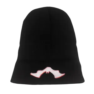 Dettaglio del berretto in maglia nero con ricamo rosso e bianco sul risvolto alto