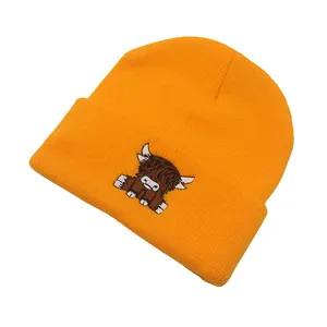 Detailed close-up of orange beanie with Scottish Highland cow embroidery on folded cuff