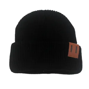 Black knit beanie for toddlers with warm folded brim and a brown leather patch detail