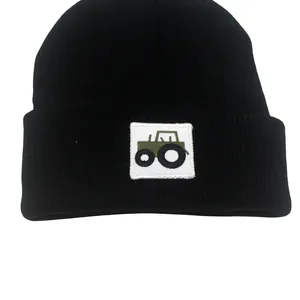 Dettaglio del ricamo a trattore su un cappello di maglia nero per neonati con risvolto