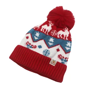 Detail van kerstgebreide muts met rendiermotief, rode pompon en zachte sneeuwvlokstructuur