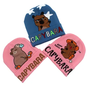 Dettagli della trama a maglia e motivi Capybara ricamati su berretti blu e rosa