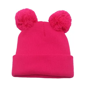 Dettaglio del berretto in maglia rosa fucsia con doppi pompon in finta pelliccia