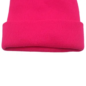Dettaglio del berretto in maglia rosa acceso con trama fine e bordo risvoltato ampio