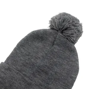 Dettaglio ravvicinato di un berretto in maglia grigio scuro con un soffice pompon