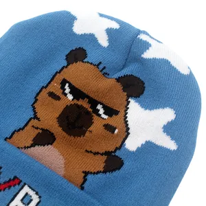 Dettaglio del berretto in maglia blu con motivo jacquard di orsetto cartoon e stelle bianche
