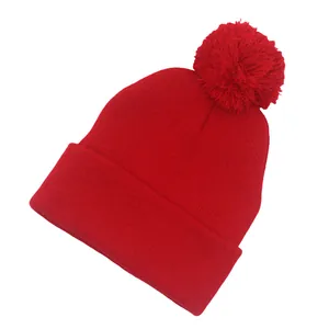 Dettaglio del berretto in maglia rossa con pompon soffice e risvolto a coste