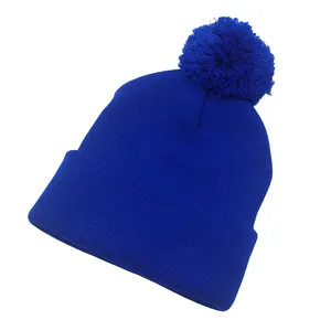 Dettaglio macro del berretto in maglia blu reale in acrilico con pompon in ecopelliccia