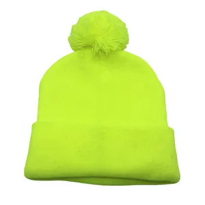Dettaglio del berretto in maglia giallo fluo con pompon morbido e bordo risvoltato