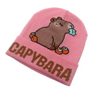 Dettaglio del berretto in maglia rosa con motivo capibara e ricamo del testo