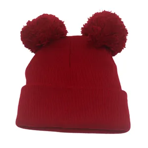 Berretto in maglia rosso scuro con due pompon e risvolto spesso per calore invernale