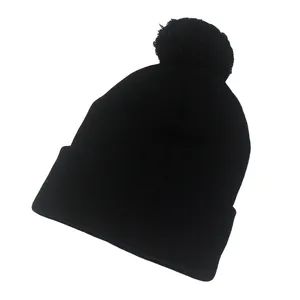 Dettaglio del berretto nero con pompon che mostra la trama spessa della maglia fitta