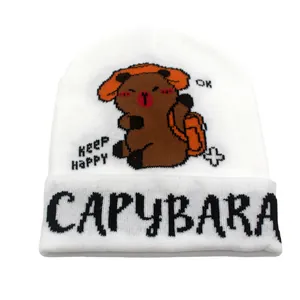 Dettaglio del berretto in maglia bianca con ricamo capybara e scritta keep happy