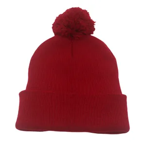 Dettaglio della trama in maglia morbida e del pompon su questo berretto rosso tinta unita