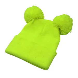 Dettaglio del cappello in maglia giallo neon con doppio pompon e bordo risvoltato
