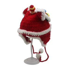 Red knit baby hat with earflaps, white pom-poms and traditional dragon decorations