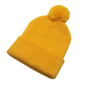 Dettaglio del berretto in maglia acrilica giallo acceso con un pompon morbido abbinato