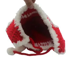 Detail of red knit kids hat showing white faux fur lining and plush pom-pom ties