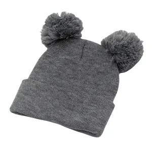 Dettaglio berretto in maglia grigio scuro con doppi pompon e trama a coste