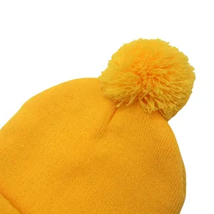 Dettaglio del berretto in maglia giallo brillante con morbido pompon e trama a coste