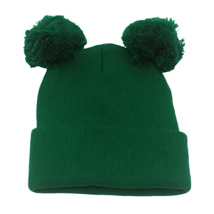 Trama a maglia dettagliata di un berretto invernale verde scuro con due grandi pompon