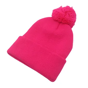 Dettaglio della trama a maglia e del pompon sul berretto di maglia rosa acceso