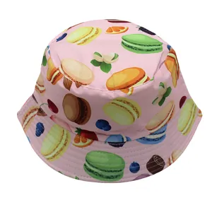 Vista detallada del sombrero rosa con patrones de macarons y frutas en algodón suave