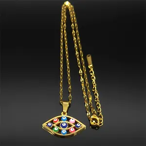 Macro detail of gold evil eye pendant with multicolor enamel eyes on black reflection