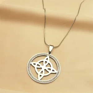 Detail of silver-tone witch knot pendant with shimmering crystals on silk background