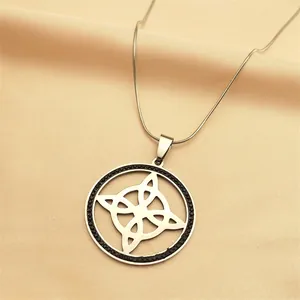 Detailed close-up of a silver witch knot pendant with black crystal halo on satin