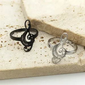 Detail of music note rings in black and silver finish on a textured stone surface