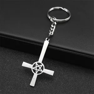 Detail of silver inverted cross keychain with pentagram star on black leather background