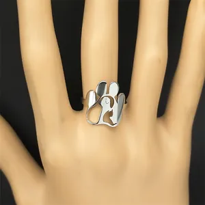 Minimalistischer silberner Ring mit Pfotenabdruck und Katzensilhouette auf schwarzem Grund