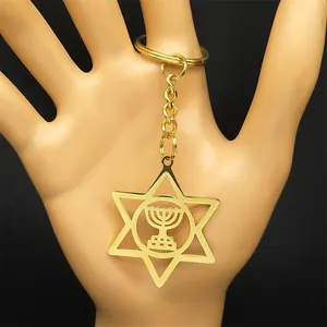 Polished gold Star of David keychain with Menorah pendant held in hand for scale